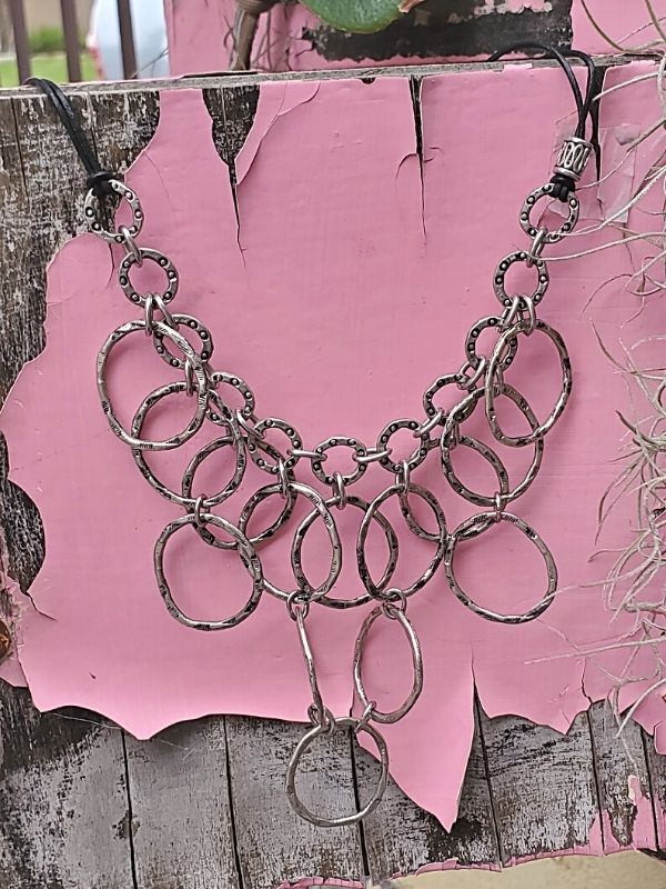 silver bib necklace on pink distressed table